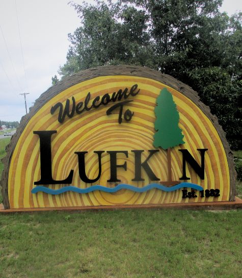 Welcome to Lufkin sign. The I in Lufkin is a Texas pine tree and the sign itself is a semicircular half of a sawn log.
